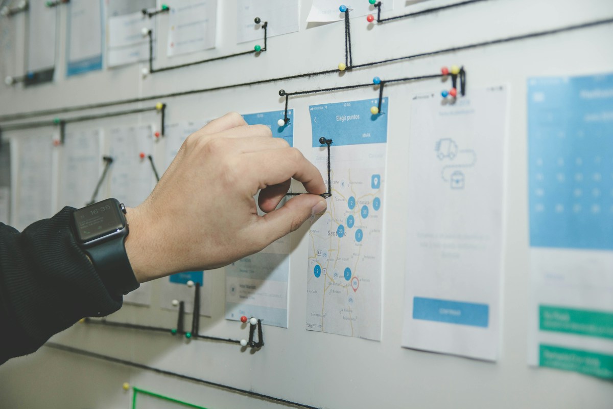 A hand arranging prototype diagrams on a planning wall