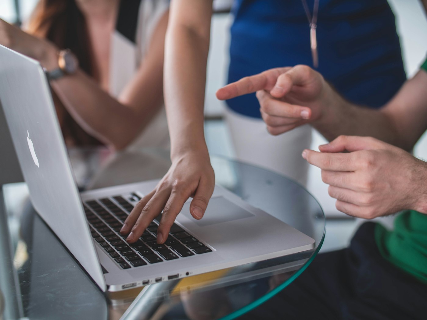 Hands pointing at a laptop while discussing a business model